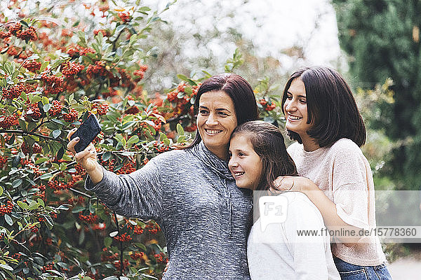Mother and daughters smiling and taking selfie