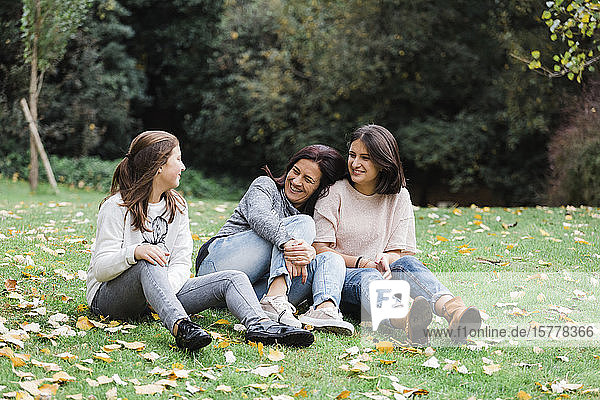 Mother and daughters sitting on grass