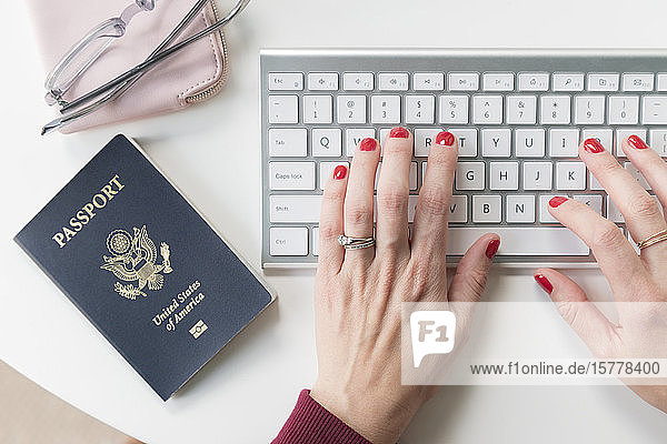 Woman typing on keyboard by passport