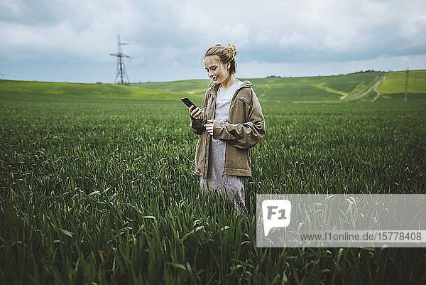 Smiling woman holding phone in field in Crimea Ukraine