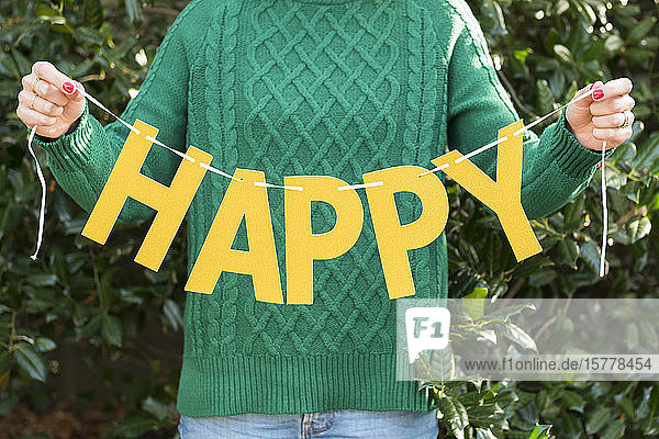 Woman holding 'happy' letters on string