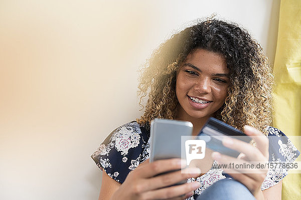 Smiling woman holding smart phone and credit card