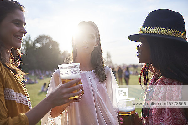 Drei junge Freundinnen mit Biergläsern beim Holi-Fest