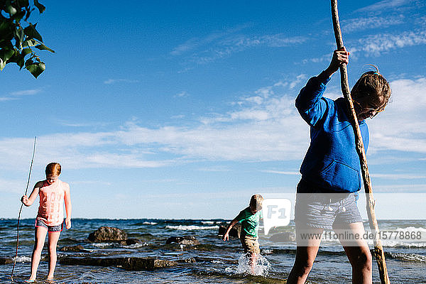Siblings exploring water with sticks  Kingston  Canada