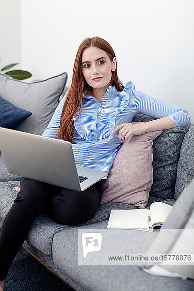 Frau benutzt Laptop auf dem Sofa