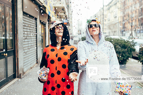 Women wearing adult bodysuits throwing confetti in street