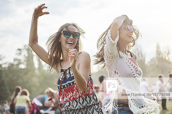 Freunde tanzen mit erhobenen Armen beim Musikfestival