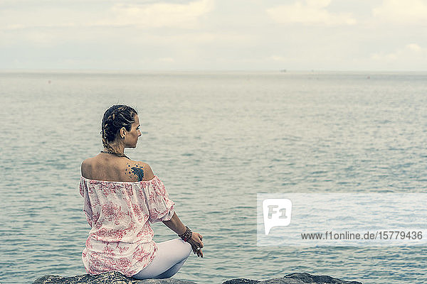 Frau meditiert auf dem Meer