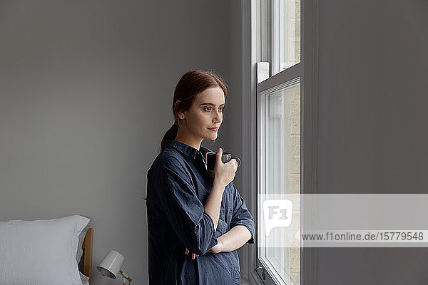 Porträt einer Frau beim Kaffee trinken am Fenster