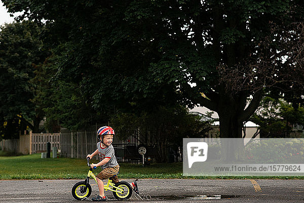 Junge fährt Fahrrad auf nasser Straße
