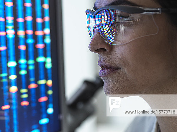 Genetische Forschung  Wissenschaftlerin  die ein DNA-Profil einer menschlichen Probe auf einem Bildschirm im Labor betrachtet.