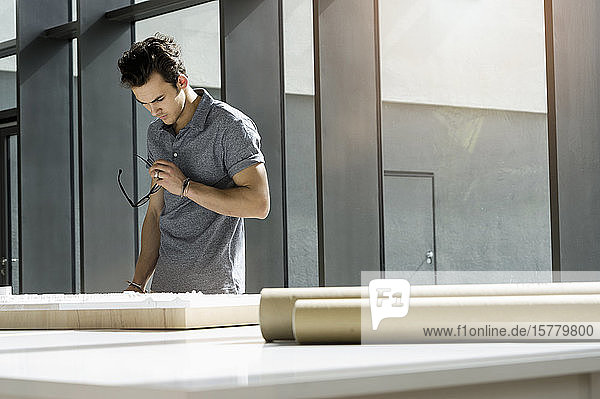 Young male architect standing at a table  working on an architectural model.