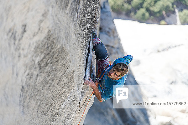 Hochwinkelaufnahme eines Bergsteigers der die steile Wand von The Nose El Capitan Yosemite National Park hinaufklettert.