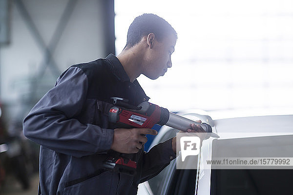 Handwerker repariert Windschutzscheibe eines Autos in der Werkstatt