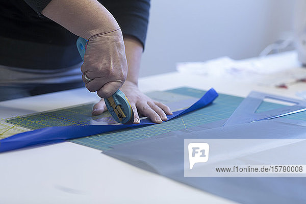 Close up of female tailor cutting blue fabric.