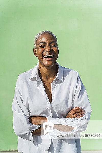 Porträt einer lachenden Frau vor grüner Wand