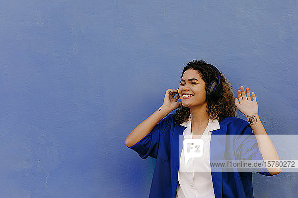 Porträt einer lächelnden Frau  die mit Kopfhörern Musik hört
