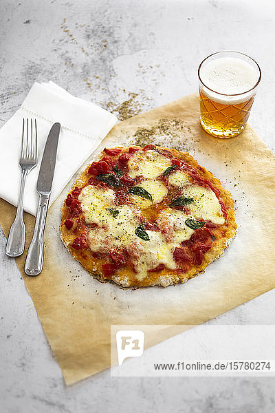 Glas Bier und verzehrfertige hausgemachte Pizza Margharita