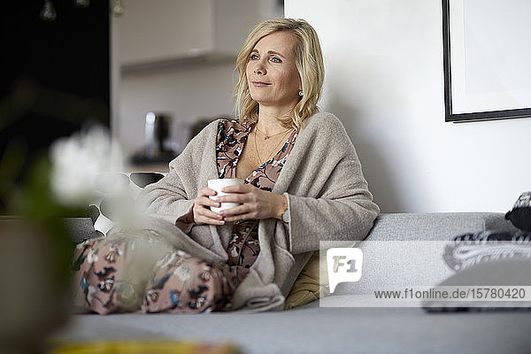 Blond woman relaxing at home sitting on couch