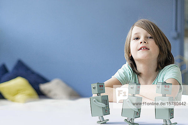 Porträt eines Jungen mit drei Spielzeugrobotern