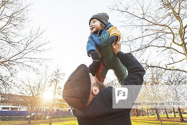 Man lifting up his happy baby son at park