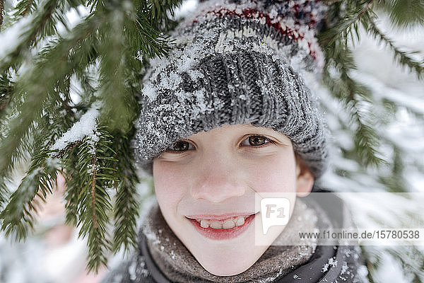 Portrait of smiling boy having fun in winter forest