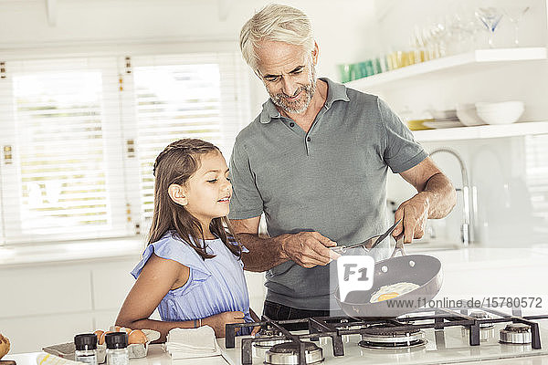 Father making fried egg for daughter at home