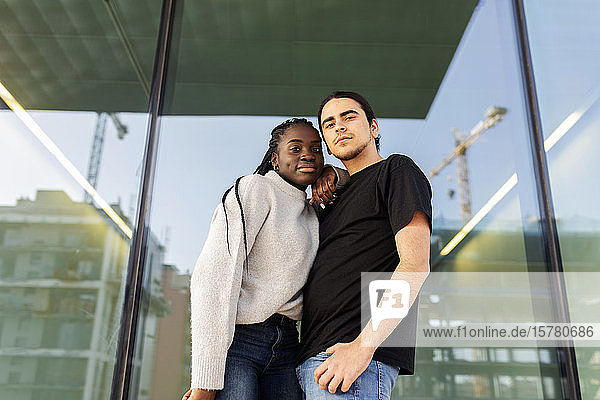 Porträt eines selbstbewussten jungen Paares an einer Glasfront stehend