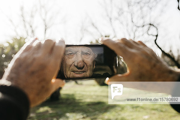 Old man taking pictutes with his smartphone
