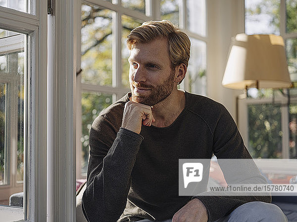 Entspannter Mann sitzt zu Hause im Wintergarten