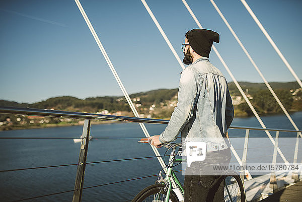 Junger Mann pendelt mit einem Fis-Fixie-Rad durch die Stadt und schaut auf das Meer