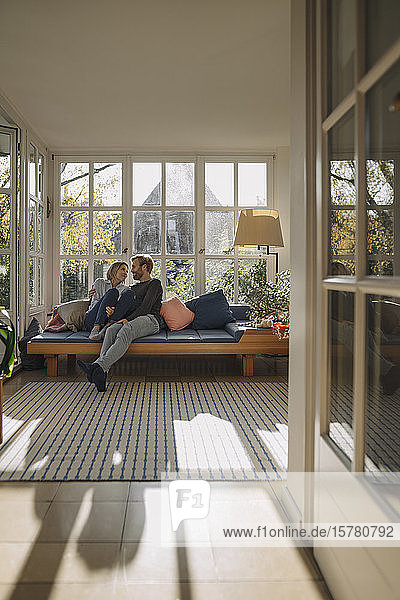 Zärtliches Paar entspannt sich zu Hause im Sonnenzimmer