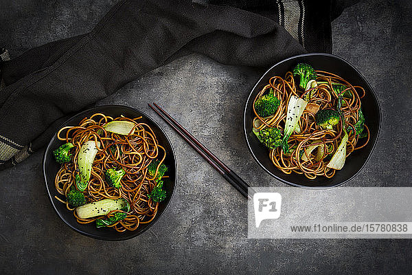 Draufsicht auf zwei Schalen Soba-Nudeln mit Pak Choi und Brokkoli Sojasauce und schwarzem Sesam