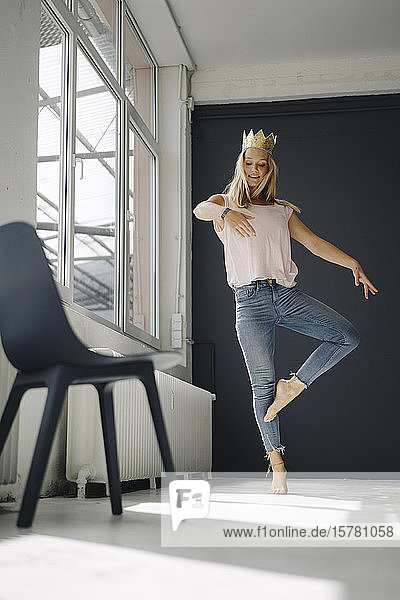 Blond young woman wearing a crown dancing in a loft
