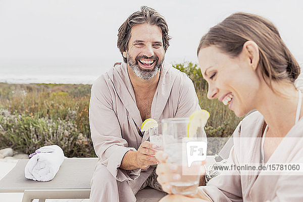 Happy relaxed couple with drinks on terrace