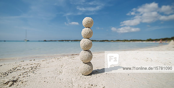 Auf einer Säule gestapelte Sandbälle am Strand Menorca Spanien
