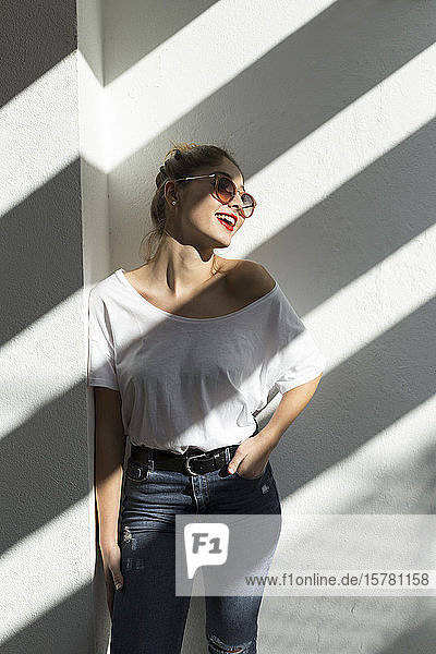 Porträt einer lachenden jungen Frau mit roten Lippen und Sonnenbrille