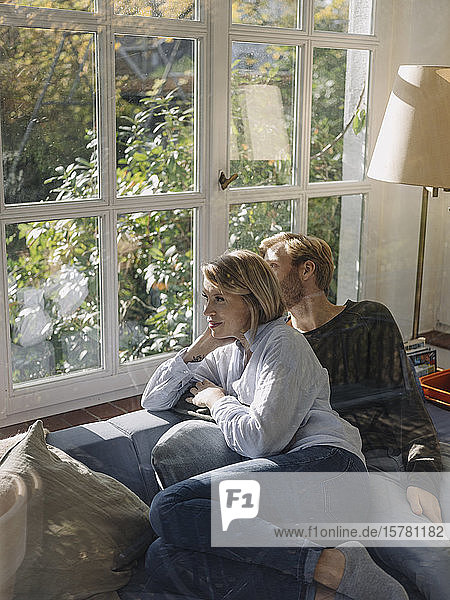 Entspanntes Paar schaut zu Hause im Wintergarten aus dem Fenster