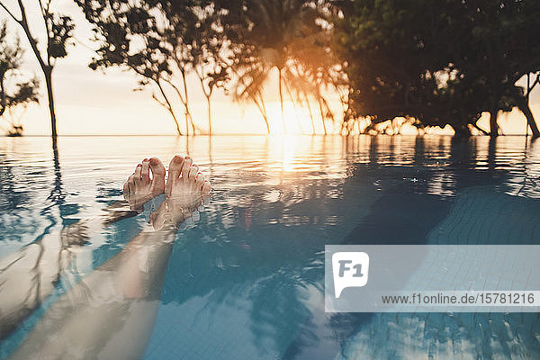 Beine einer Frau im Infinity-Pool bei Sonnenuntergang  Nai Thon Beach  Phuket  Thailand