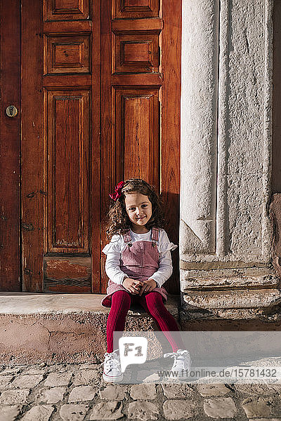 Portrait of smiling girl sitting on front stoop