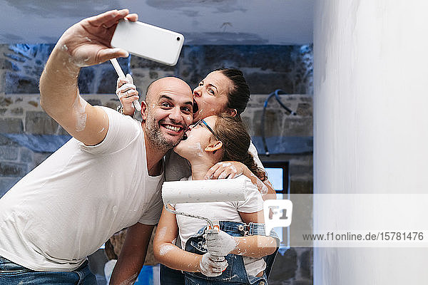 Happy family taking a selfie while painting the walls of her new house