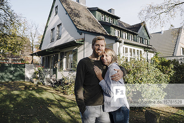 Portrait of smiling couple standing in front of their home