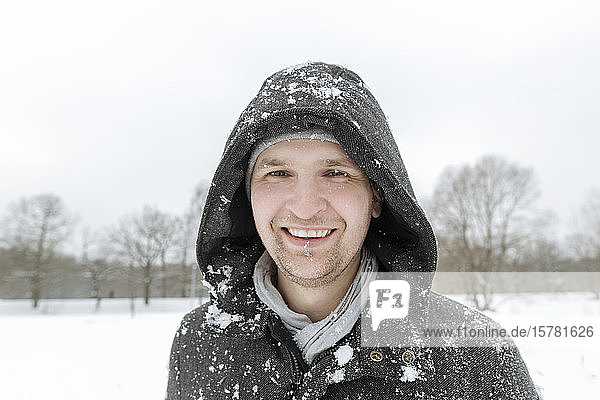 Portrait of happy man in winter landscape with snowfall