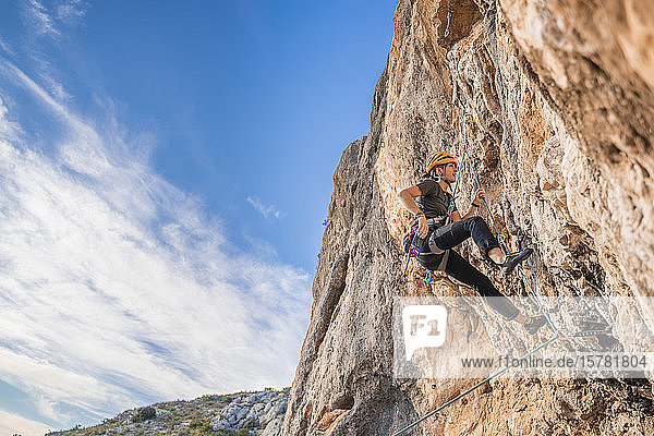 Frau klettert an Felswand