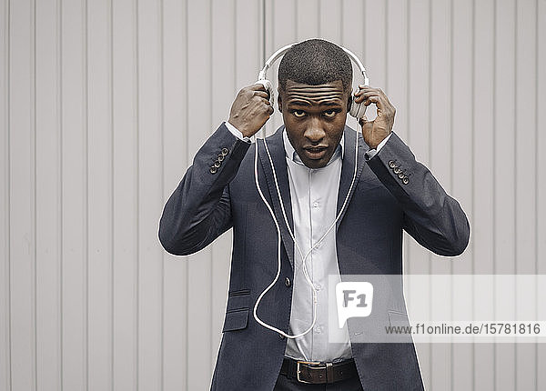 Portrait of young businessman putting on headphones