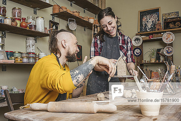 Zwei Töpfer arbeiten gemeinsam an einem kleinen Haus in einer Werkstatt