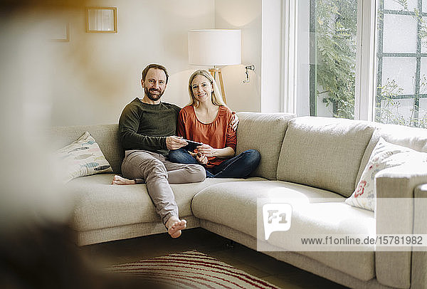 Couple sitting at home on couch  using digital tablet