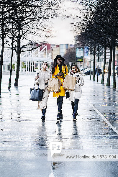 Freundinnen  die an einem regnerischen Tag in der Stadt spazieren