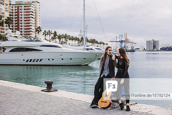 Junges Paar mit einer Gitarre am Hafen