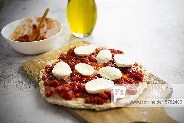 Halbfertige Pizza Margharita auf Schneidebrett